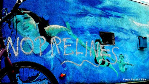 Business mural with &quot;No Pipelines&quot; spray painted on it, Commercial Drive, Vancouver.